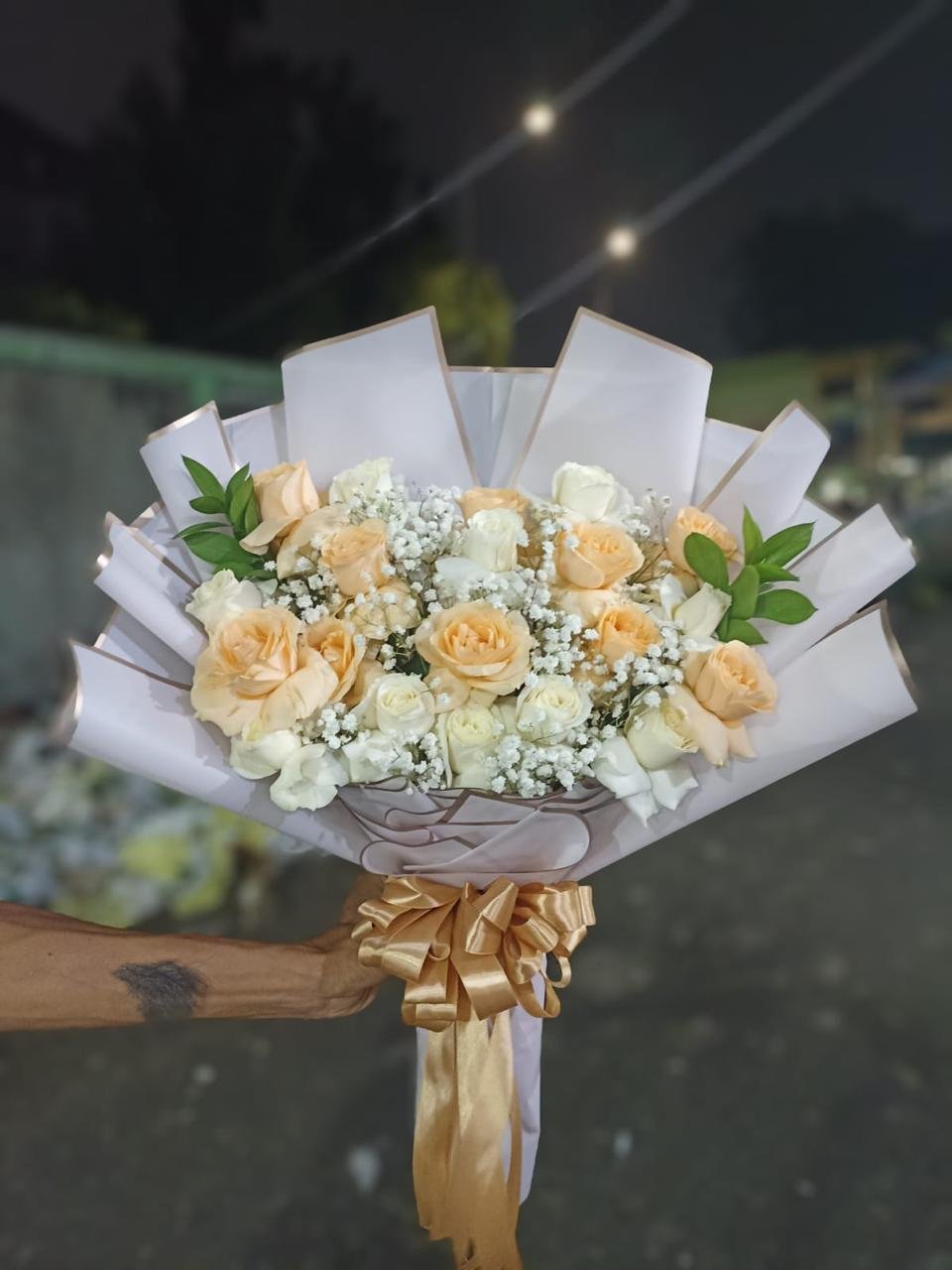 Hand bouquet mawar peach cream putih dengan baby breath, wrap kertas putih dan pita emas elegan untuk anniversary